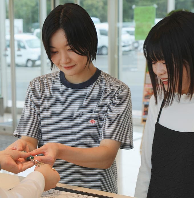 カウンター越しに人物が鍵を受け取っている様子、隣にもう一人の人物が立っている