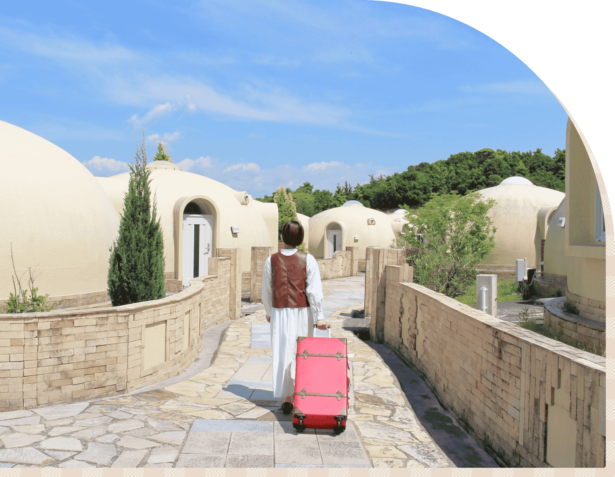 とれとれヴィレッジの敷地内で、ドーム型コテージへ向かってスーツケースを引く旅行者